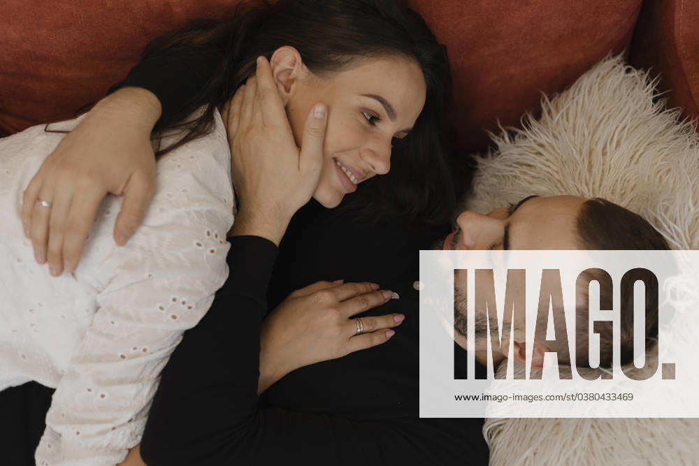 Young man lying down and embracing woman at home model released, Symbolfoto, EHAF00154