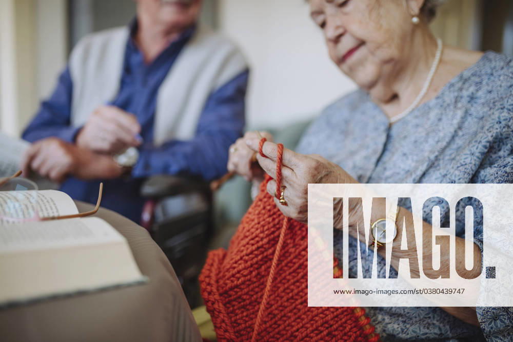 Senior woman knitting wool with man sitting in background model released, Symbolfoto property released, HAPF03269