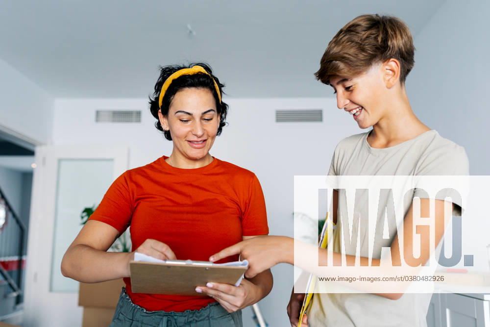 Mother and son checking notes on clipboard together and smiling Content woman and son smiling and reading notes on clipboard while discussing details of new ideas Model Released SergioVictorVega_ID17443_529444_016