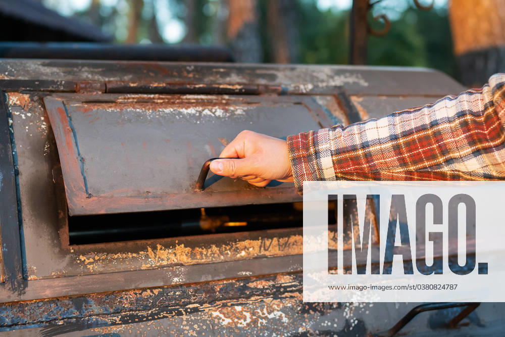 A man in a frilly shirt is looking at an excellent professional grill for re-frying meat. Professional outdoor BBQ. A man in a frilly shirt is looking at an excellent professional grill for re-frying meat. Professional outdoor BBQ