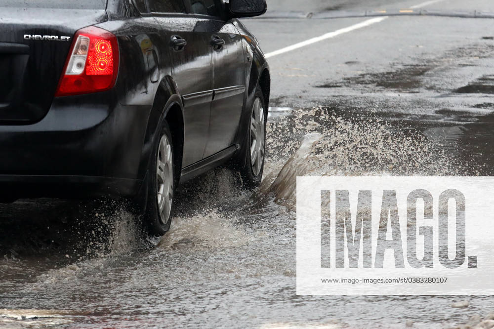 VYSHNEVE, UKRAINE - JANUARY 04, 2024 - A car drives through a deep puddle on the street, Vyshneve, Kyiv region, north-central Ukraine Wintertime in Vyshneve
