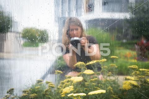 Portrait of woman taking photographs of flowers outside. camera mirror outdoor photographer portrait rain reflection selft-portrait glass skyscraper park woman wet urban selfie self-expression reflective plants photography lifestyle hobby flowers creativity cityscape caucasian casual adult 40-50 years washington district of columbia united states fourties 40-49 years old one person male black