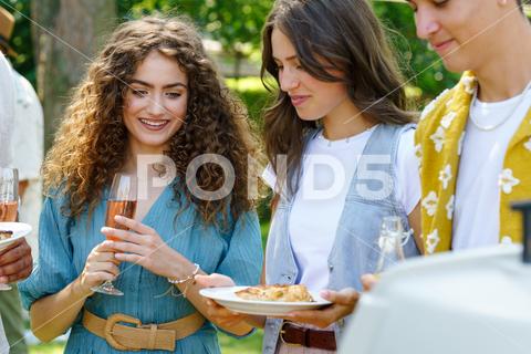 Friends and family talking and eating barbeque specialties at a summer grill garden party. friends family bbq talking fun grill garden party people laughing holding glasses drinks Barbeque specialties alcoholic non-alcoholic diverse toast enjoyment gathering celebration socializing outdoor happiness lemonade leisure bonding togetherness relaxation conversation memories entertainment cheerful atmosphere food beverages warmth joy camaraderie laughter festivity event sunlight nature copy space green birthday birthday party