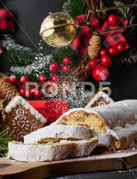Christmas pastries stollen sprinkled with powdered sugar on the table, festive dessert stollen cake sweet holiday food traditional dessert pastry german nobody celebration baked winter bread bakery christmas fruit sugar festive fruitcake powdered wooden slice raisin nut white
