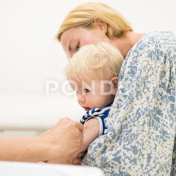 Child beeing vaccinated by pediatrician in presence of his mother. Preventive vaccination against Diphtheria, whooping cough, tetanus, hepatitis, haemophilus influenzae, pneumococcus, poliomyelitis. toddler arm pediatrician vaccination syringe clinic prevention infant virus vaccinating medicine medical health practitioner little vaccine injection patient nurse doctor healthcare immunization childhood protection pediatric infection caucasian disease care woman therapy intramuscular outbreak infectious immunity epidemic medication injecting physician length drug parent mom mother present preventive comfort boy