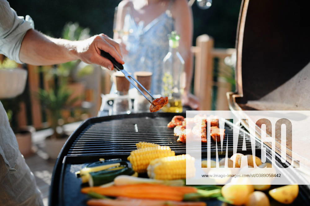 Unrecognizable man grilling ribs and vegetable on grill during family summer garden party, close-up An unrecognizable man grilling ribs and vegetable on grill during family summer garden party model released