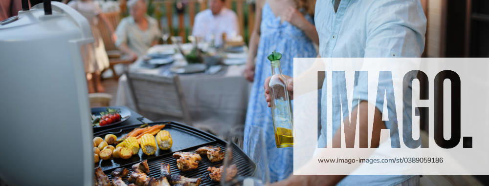 Unrecognizable man grilling ribs and vegetable on grill during family summer garden party, close-up An unrecognizable man grilling ribs and vegetable on grill during family summer garden party model released