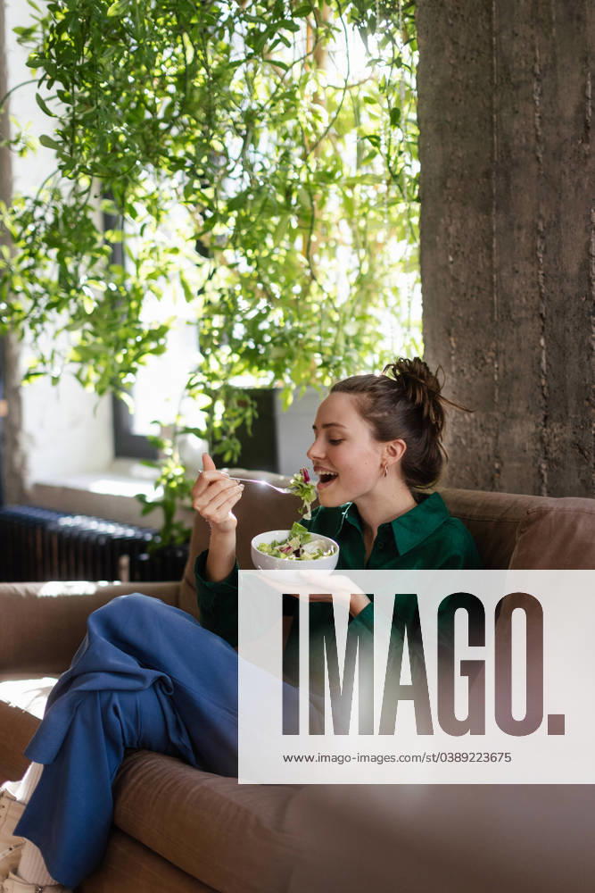 Young woman eating salad in an office. Young woman having lunch in the office. model released