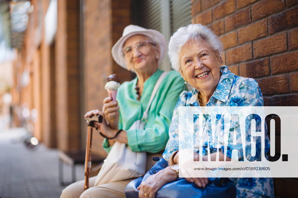 Portrait of two senior female friends in the city, eating ice cream on a hot summer day. Portrait of two senior female friends in the city, eating ice cream on a hot summer day. Elderly ladies on summer vacation in the city. Pensioners on group trip. Concept of senior vacation and travel groups, clubs. model released