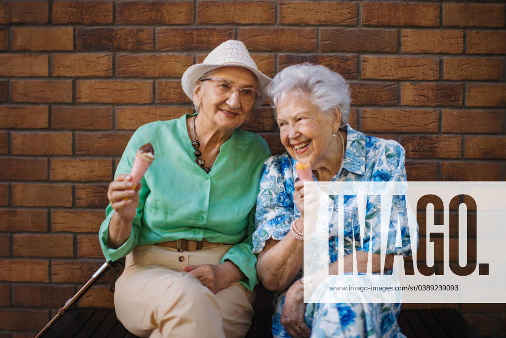 Portrait of two senior female friends in the city, eating ice cream on a hot summer day. Portrait of two senior female friends in the city, eating ice cream on a hot summer day. Elderly ladies on summer vacation in the city. Pensioners on group trip. Concept of senior vacation and travel groups, clubs. model released