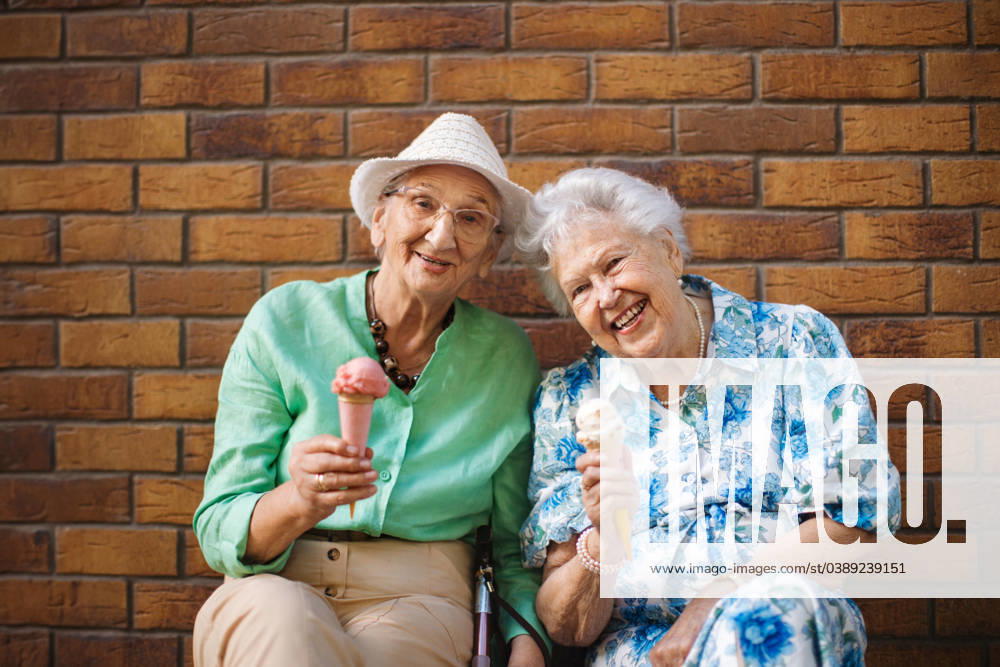 Portrait of two senior female friends in the city, eating ice cream on a hot summer day. Portrait of two senior female friends in the city, eating ice cream on a hot summer day. Elderly ladies on summer vacation in the city. Pensioners on group trip. Concept of senior vacation and travel groups, clubs. model released