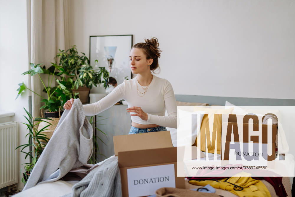 Young woman giving her clothes to charity. Young woman giving her clothes packed in box to charity. model released