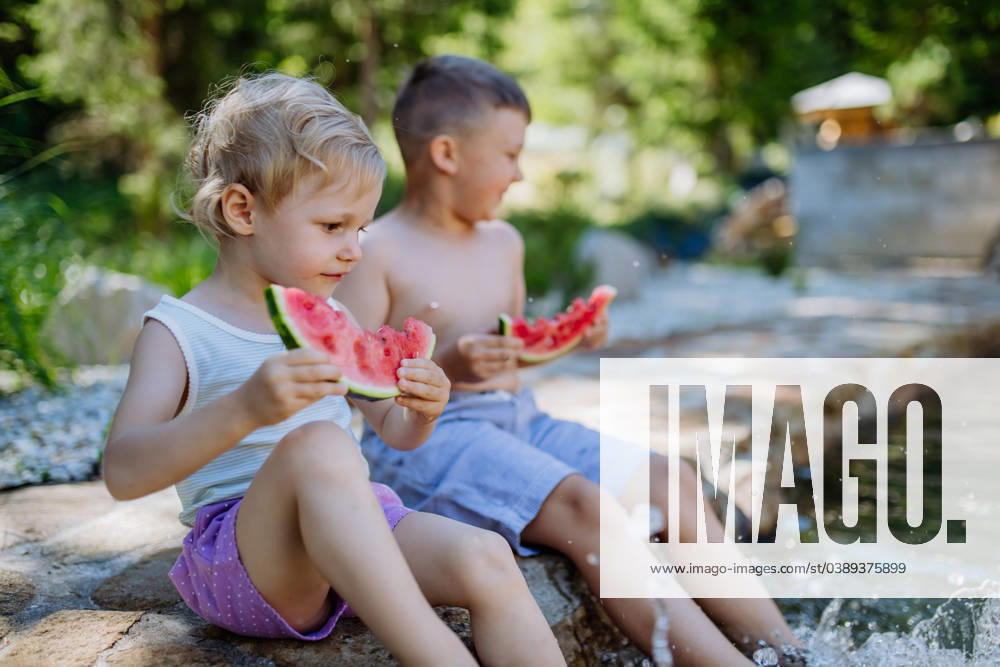 Little chidren sitting near lake and eating watermelon on hot sunny day during summer vacation. Little chidren sitting near a lake and eating watermelon on hot sunny day during summer vacation. model released