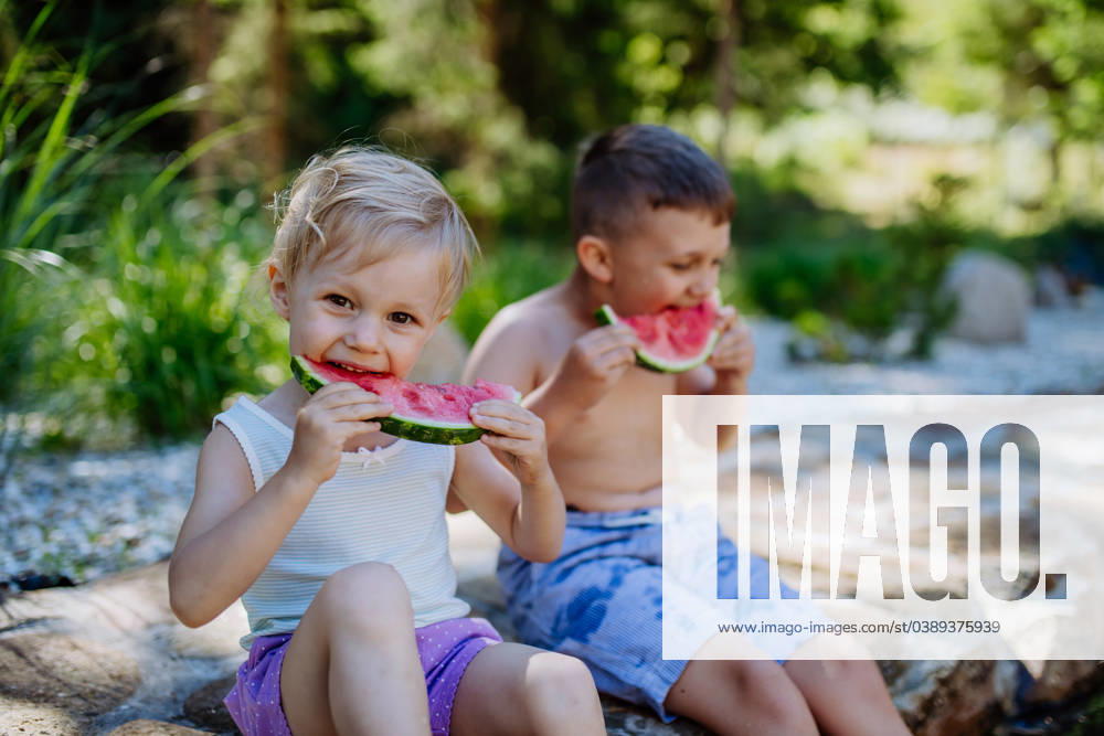 Little chidren sitting near lake and eating watermelon on hot sunny day during summer vacation. Little chidren sitting near a lake and eating watermelon on hot sunny day during summer vacation. model released