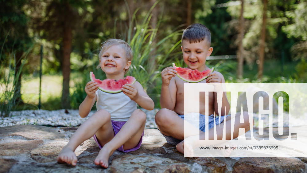 Little chidren sitting near lake and eating watermelon on hot sunny day during summer vacation. Little chidren sitting near a lake and eating watermelon on hot sunny day during summer vacation. model released
