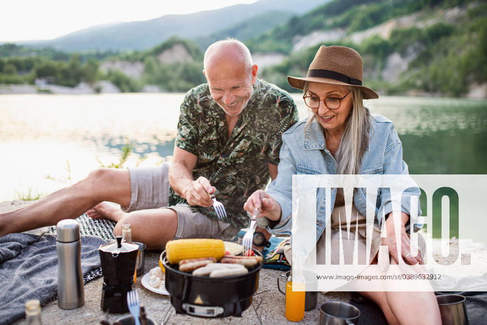 Happy senior couple resting on summer holiday trip, barbecue by lake. Portrait of happy senior couple resting on summer holiday trip, barbecue by lake. model released