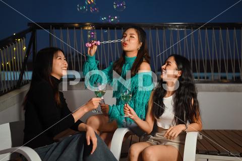 Young friends gathered together having fun toasting champagne and blowing soap bubbles at the rooftop night party rooftop friendship celebrating person alcohol terrace evening outdoors lifestyles group friends celebration smiling drink happiness togetherness enjoyment joy carefree young adult weekend laughing bar balcony cheer talking urban relaxation pub roof sky enjoying beverage restaurant entertainment event festival adolescence festive chatting having fun joyful union friday nightlife nightclub adult