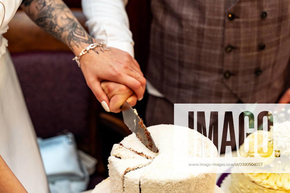 A bride and groom cut a wedding cake together at their wedding