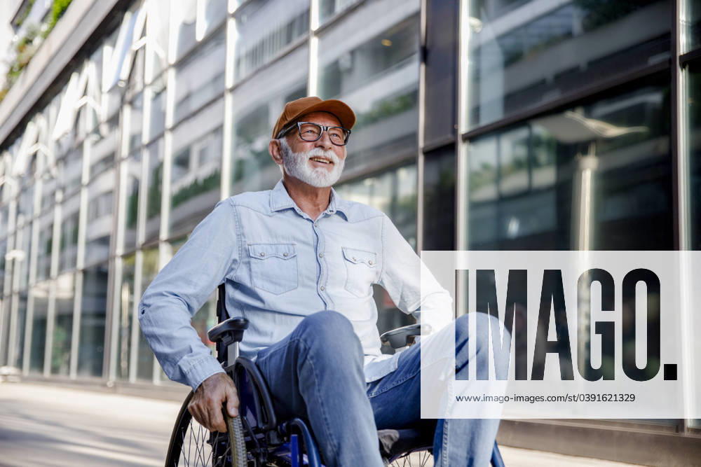 Smiling senior man sitting in wheelchair on footpath model released, Symbolfoto, IKF01382