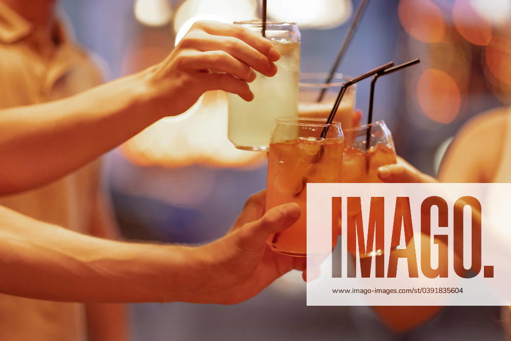 Closeup of female and male hands holding glasses with cocktails with ice and clicking them. Friends make a festive toast with delicious citrus drinks through a straw. Closeup of female and male hands holding glasses with cocktails with ice and clicking them. Friends make a festive toast with delicious citrus drinks through a straw. Party, birthday, vacation concept ,model released, Symbolfoto