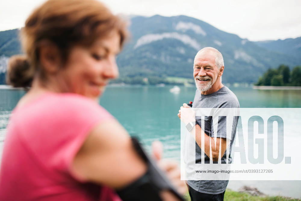 Senior pensioner couple runners with smartphone by lake in nature. Senior pensioner couple runners with smartphone by lake in nature, resting. model released