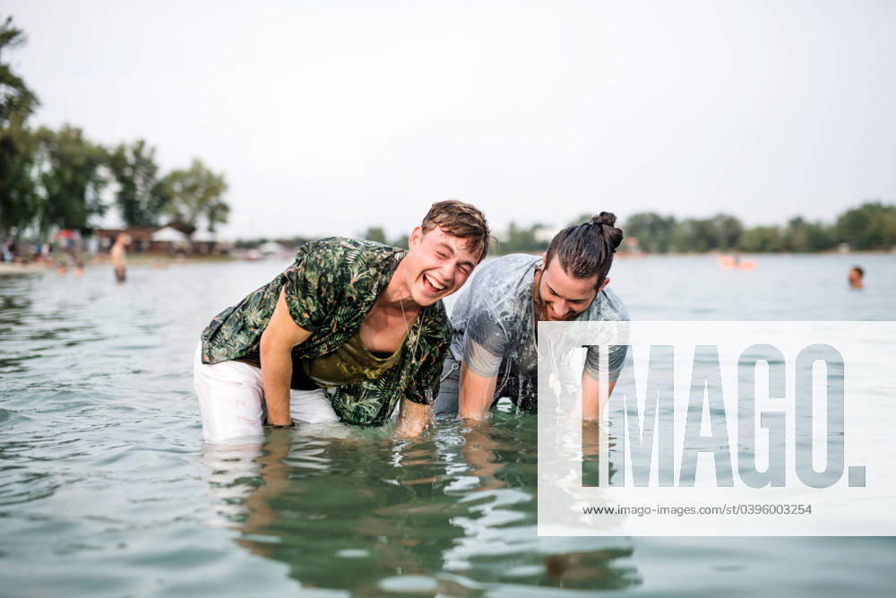 Wet young men friends at summer festival, standing in lake. Wet young men friends at summer festival, standing in lake and looking at camera. model released