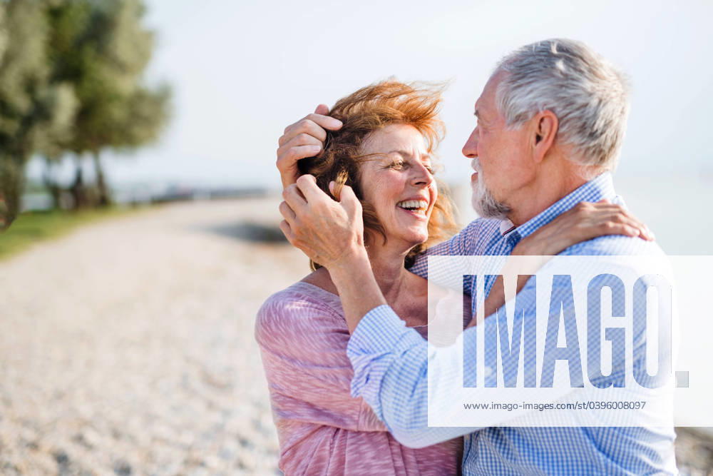 Senior couple on a holiday on a walk by the lake, hugging. Front view of senior couple on a holiday on a walk by the lake, hugging. model released