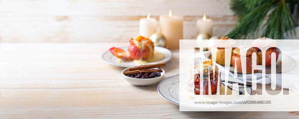 German baked apples wit powdered sugar and vanilla sauce, stuffed with almonds, honey and rosins on a light wooden background, Christmas time dessert, panoramic format, copy space German baked apples wit powdered sugar and vanilla sauce, stuffed with almonds, honey and rosins on a light wooden background, Christmas time dessert, panoramic format, copy space, selected focus