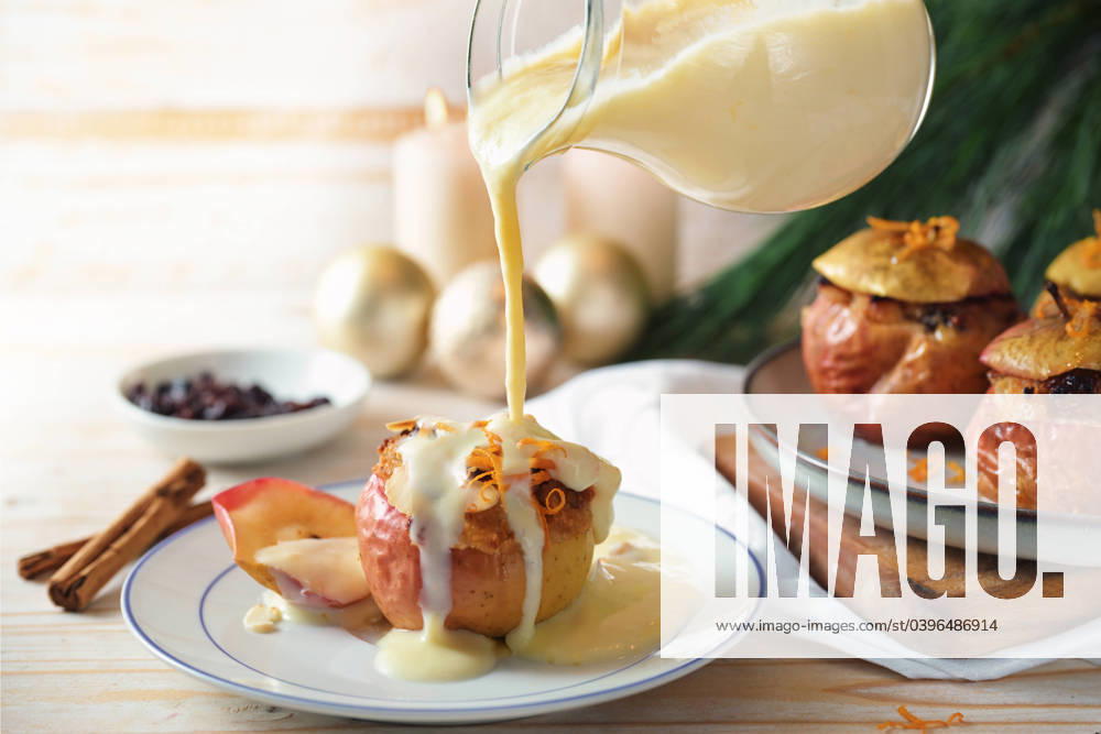 Pouring vanilla sauce on a baked apple filled with almonds, honey and raisins, homemade winter dessert for holidays like Christmas, Thanksgiving or new year, copy space, selected focus Pouring vanilla sauce on a baked apple filled with almonds, honey and raisins, homemade winter dessert for holidays like Christmas, Thanksgiving or new year, copy space, selected focus