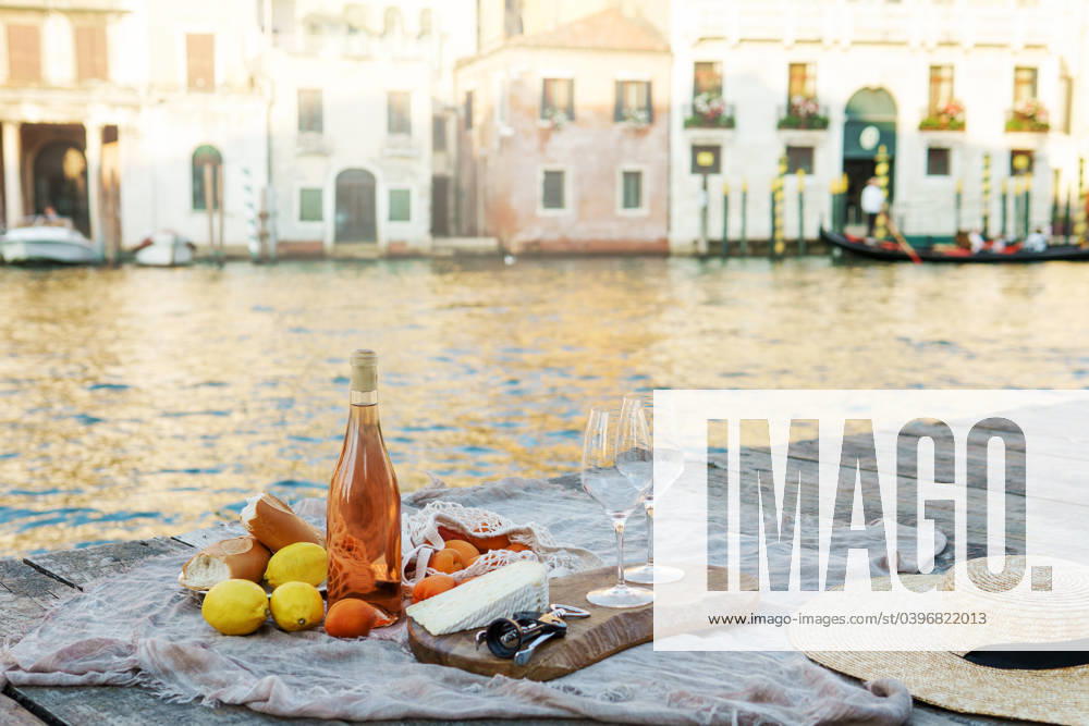 Rose wine, fruits and snacks on the wooden pier during picturesque picnic on the wooden dock Rose wine, fruits and snacks on the wooden pier during picturesque picnic on the wooden gondola dock