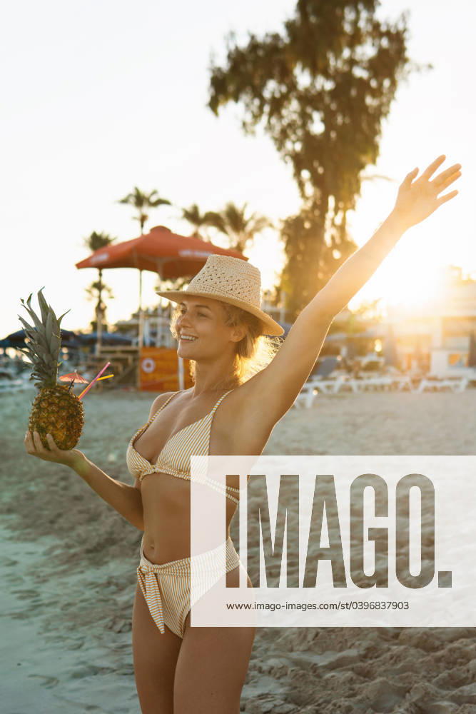 Young happy woman enjoying cocktail in pineapple during sunset on the beach Young happy woman enjoying cocktail in pineapple during sunset on the beach. ,model released, Symbolfoto