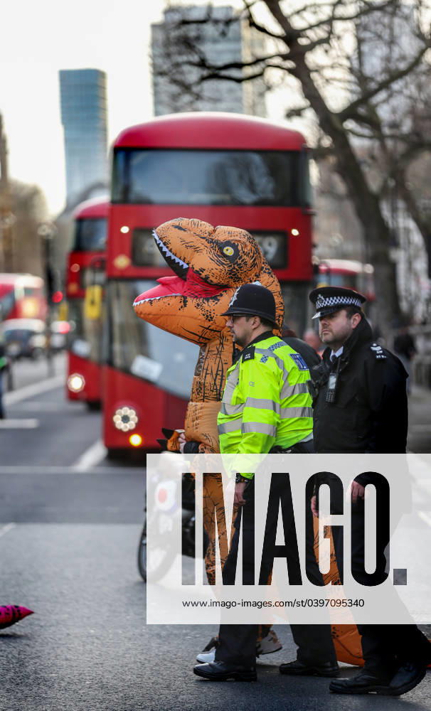 Police officers try to clear the street as protesters dressed in inflatable dinosaur costumes block the road outside Downing Street. Protesters gather for their first-anniversary protest against the Ultra Low Emissions Zone (ULEZ). Protesters claim the expansion of the zone last year is killing businesses and hitting the self-employed. London United Kingdom - ZUMAs197 20240127_aaa_s197_188