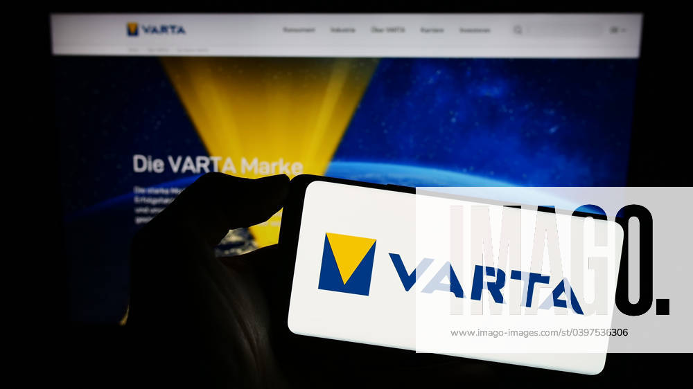 Person holding smartphone with logo of German battery company Varta AG on screen in front of website Stuttgart, Germany - 09-11-2023: Person holding smartphone with logo of German battery company Varta AG on screen in front of website. Focus on phone display.
