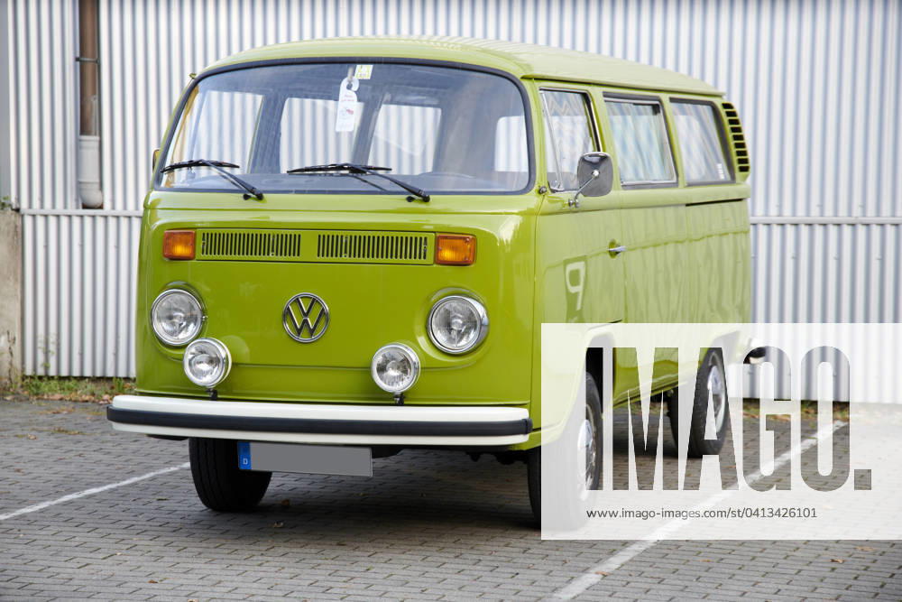 Oldtimer VW Bulli T2 a Very Maintained Grasshopper gruener VW Bulli T2 is at a marked Car park before a white Corrugated iron wall Food