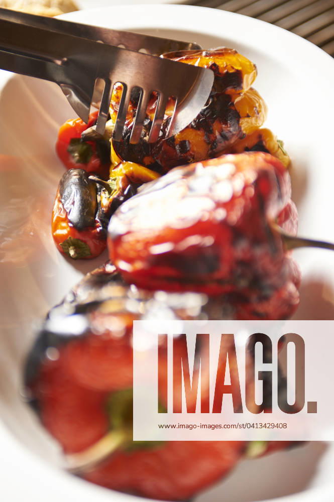 Grilled Peppers red and Yellow Peppers at a Crying Serving dish become with a Barbecue tong raised Food