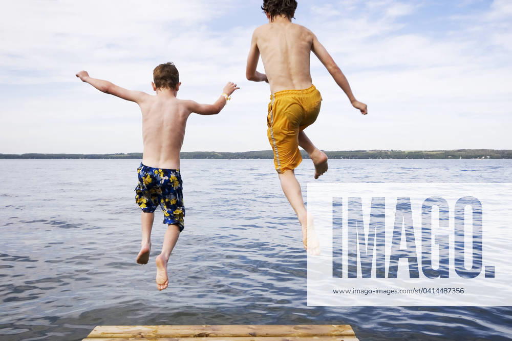 Two boys (9 & 12 years old) jumping off dock into lake, Sylvan Lake, Alberta. model released MR_acp05766a, MR_acp05766c