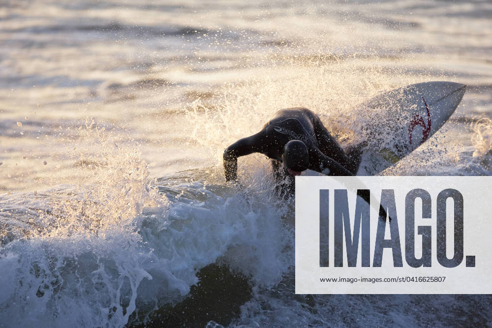 A surfer ripping through the crest of a wave in Rosie Bay, Tofino, Vancouver Island, British Columbia, Canada