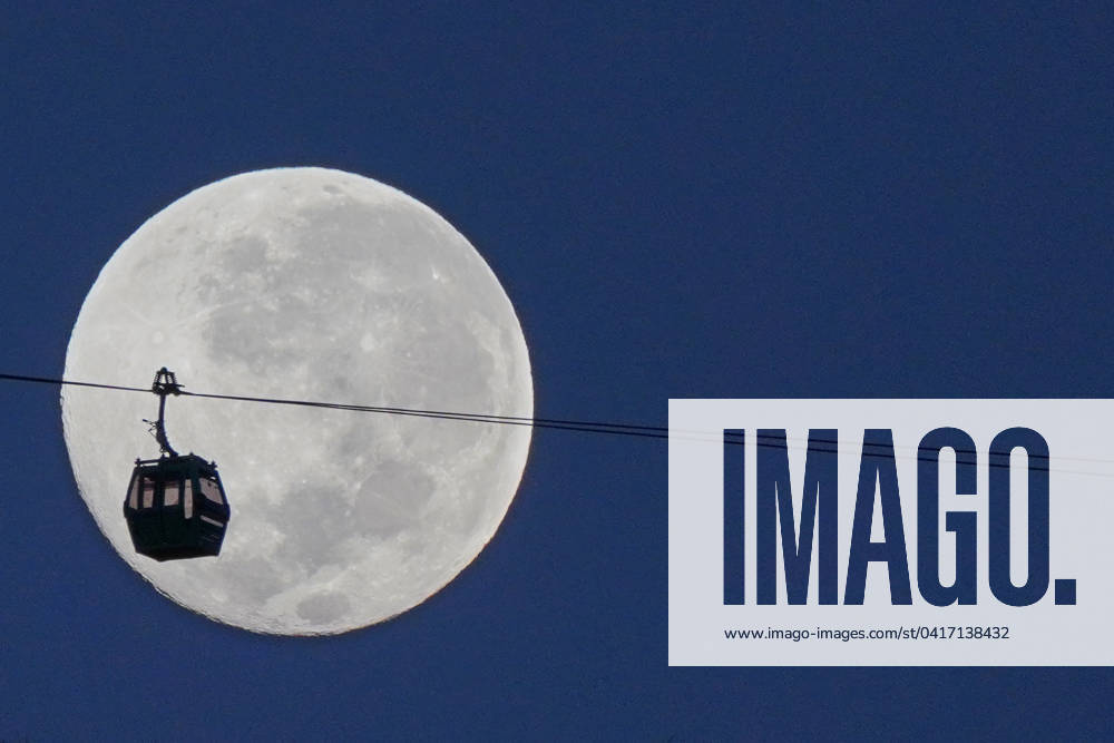 The full moon sets behind a cable car on San Cristobal hill in Santiago, Chile. Santiago Chile - ZUMAb332 20240225_zip_b332_002