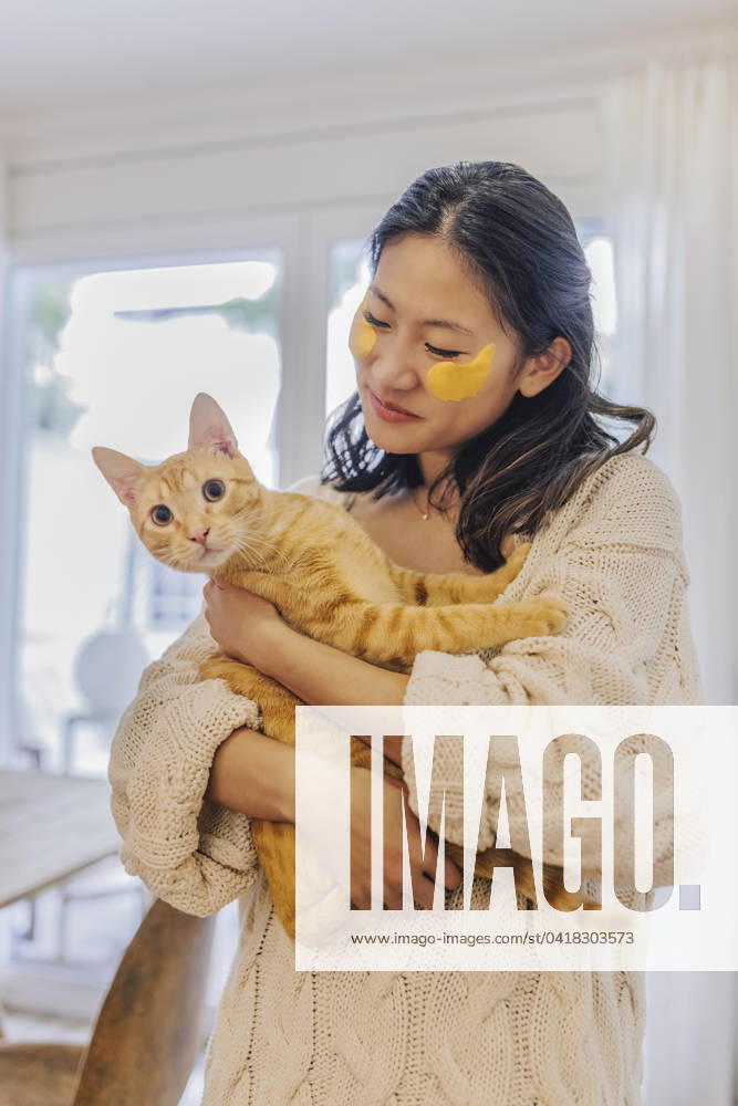 Smiling woman with under eye patches holding cat at home model released, Symbolfoto property released, ASNF00027