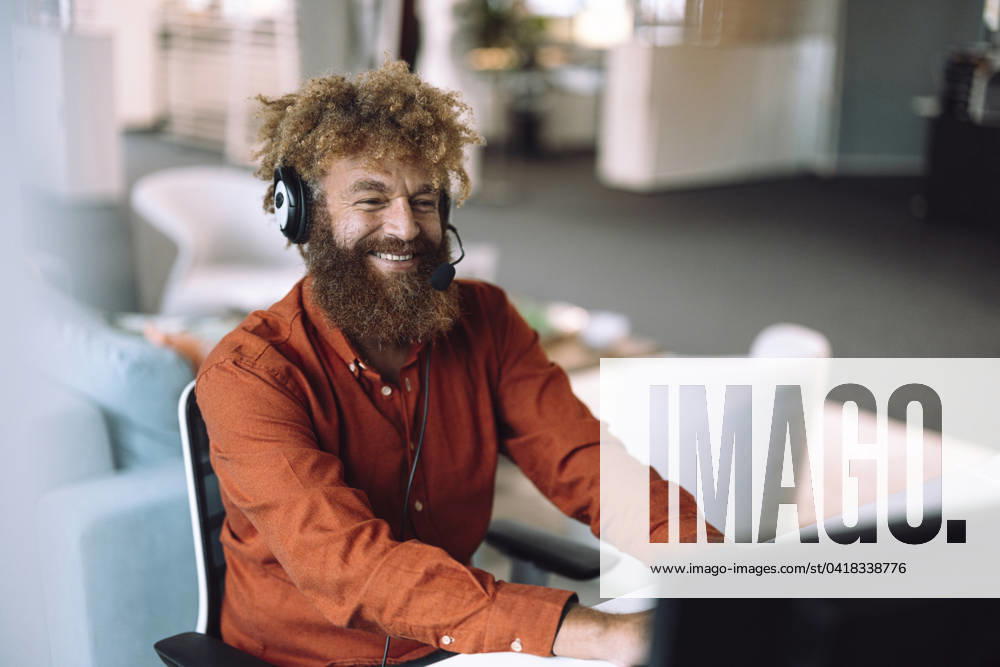 Happy businessman wearing headset and working on computer in office model released, Symbolfoto property released, JOSEF23334