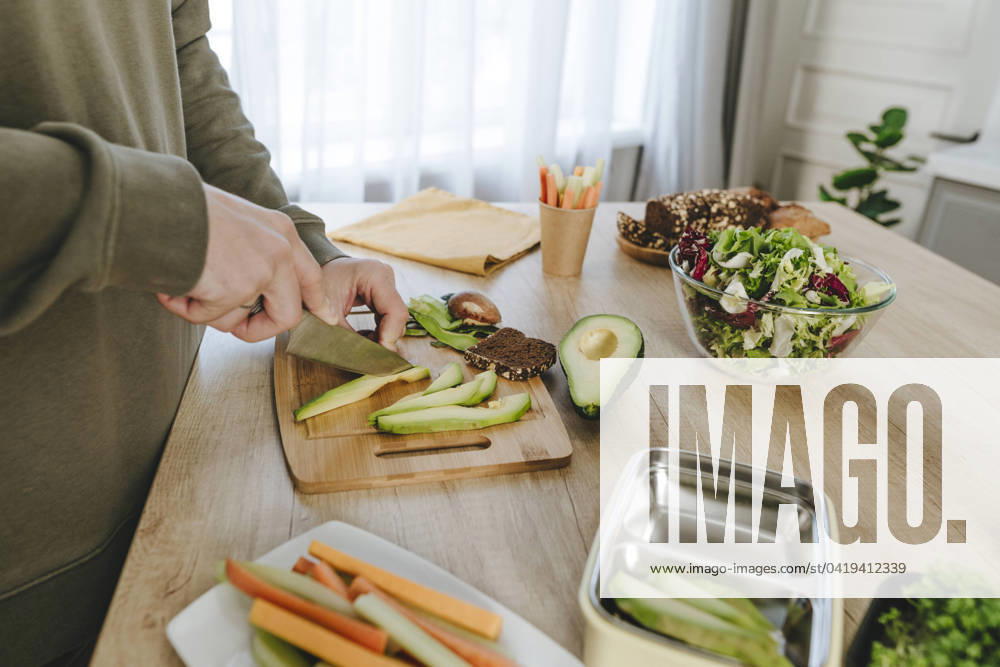 IMAGO Creative, Food, Trend, Meal Prep Man cutting avocado with knife in kitchen at home model released, Symbolfoto property released, YTF01680