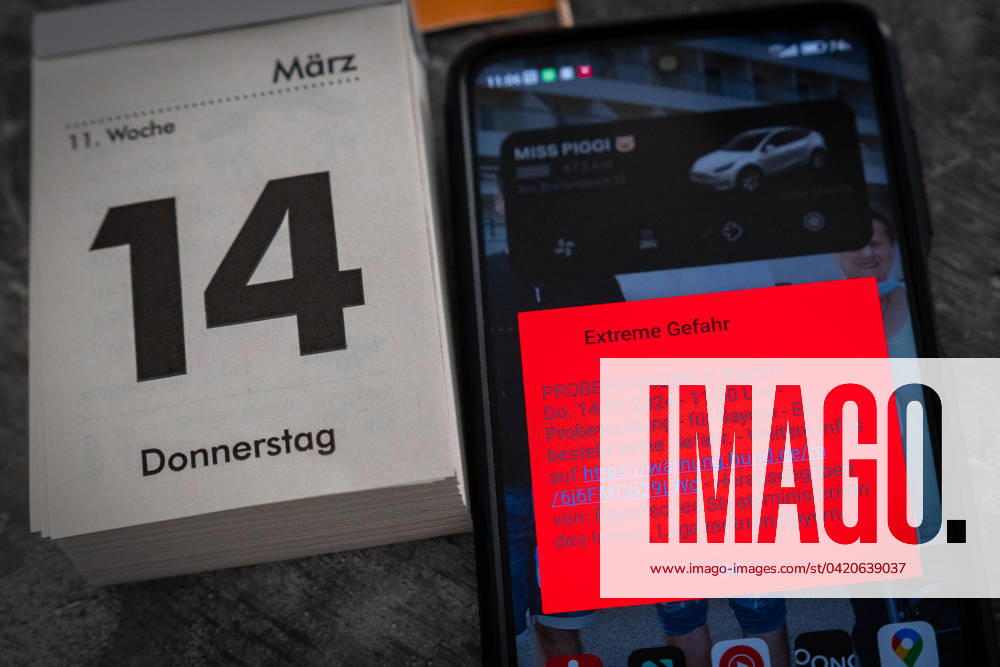 Theme picture test alarm on March 14 at 11 a.m. in Bavaria. Smartphone with the warning message: Extreme danger, on the screen
