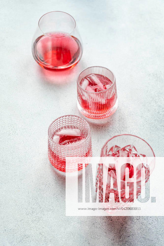 Top view of elegant glasses filled with a refreshing cherry vodka and tonic cocktail, accompanied by ice cubes, set on a textured surface. Model Released AnnaBogush_ID19984_591795_002