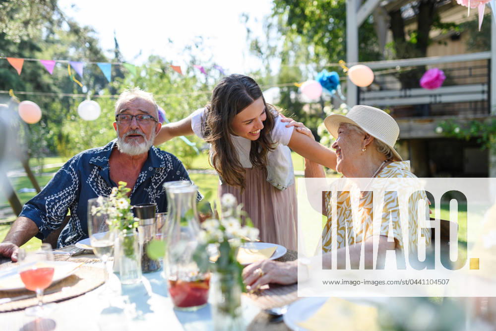Mature granddaughter talking with grandparents, reunite after a long time. Family gathering at garden party. Mature granddaughter talking with grandparents, reunite after a long time. Family gathering at a garden party. model released