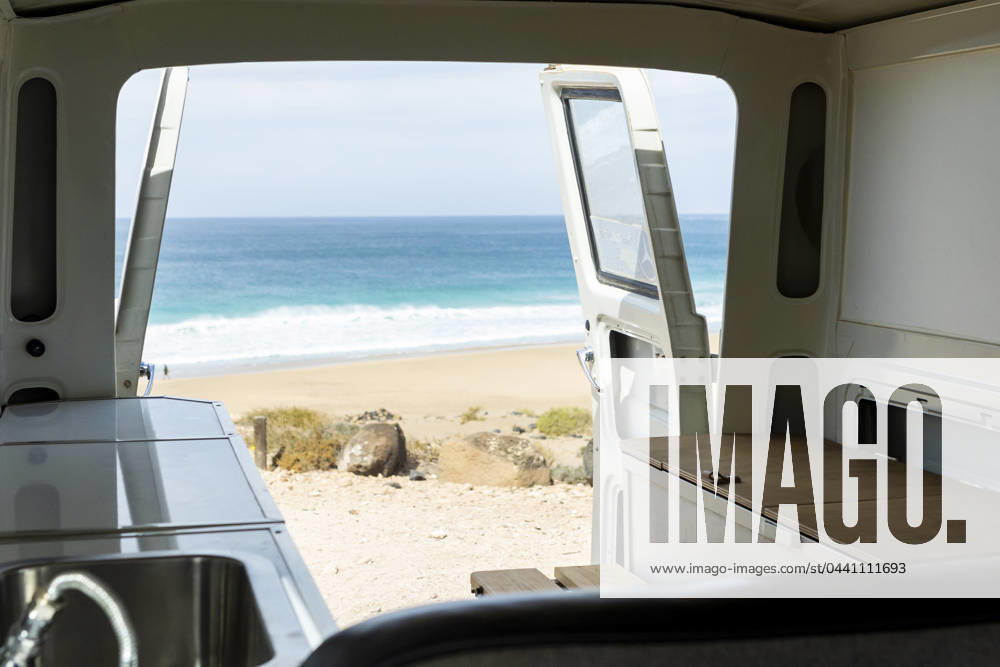 Experience tranquility through the open back of a vintage van overlooking a serene beach scene. Model Released JuanAizpuru_ID19709_584436_003