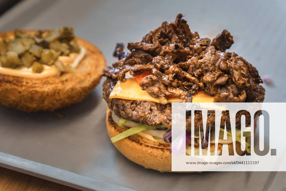 Prepared Philly cheese burger on a tray in a snack bar with fresh beef, tomato, lettuce and toasted hamburger bun