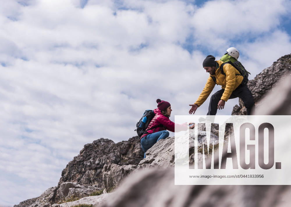 Man helping girlfriend in climbing up on mountain at Bavarian Alps, Germany model released, Symbolfoto, UUF31460