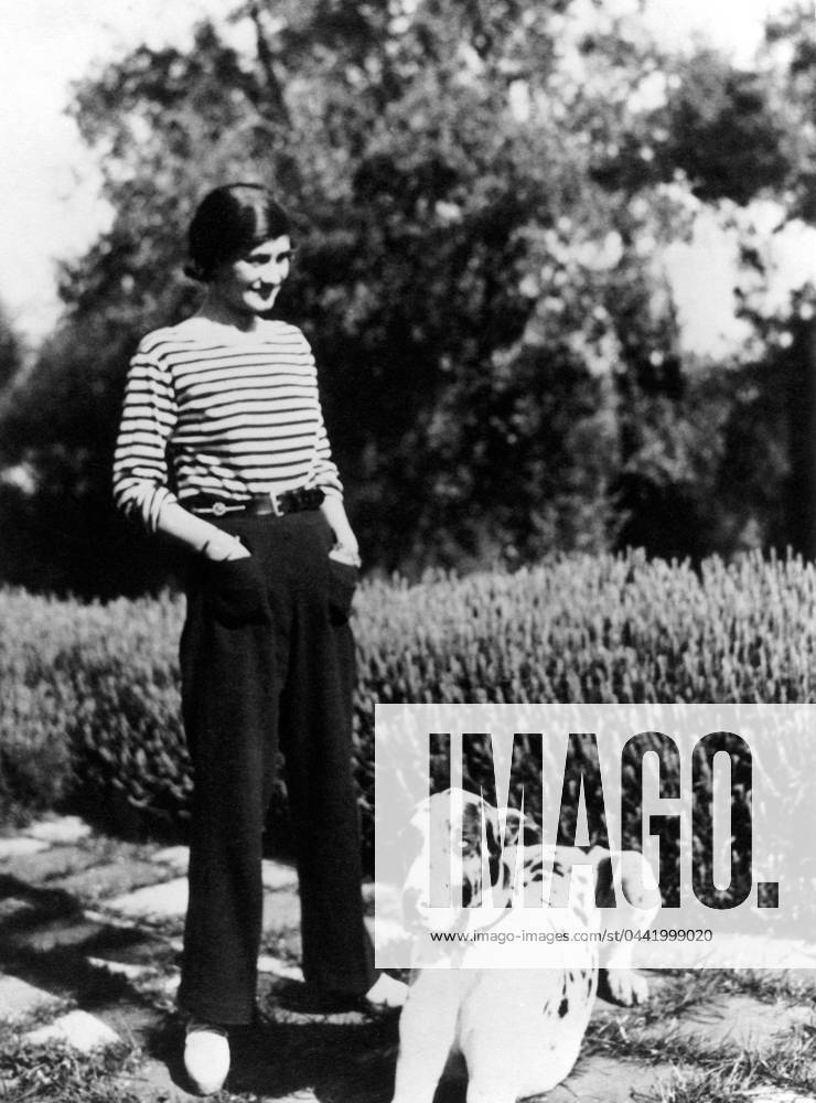 GABRIELLE COCO CHANEL (1883-1971). French fashion designer. Photographed at her home, Villa La Pausa in Roquebrune, in the French Riviera, with her dog, Gigot, c1930.