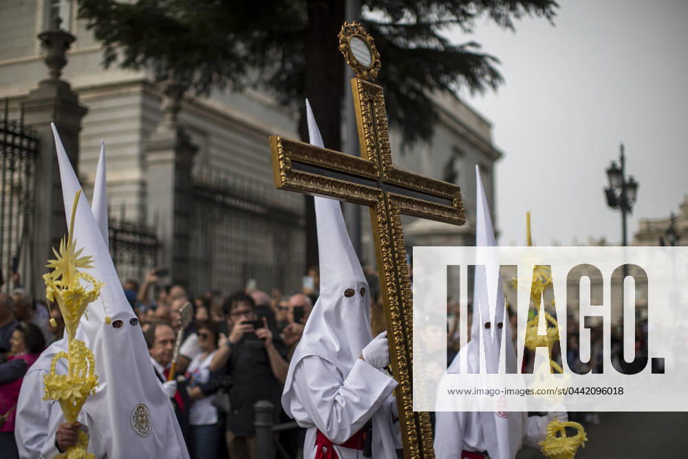 A penitent holds a large cross at the exit of Madrid s La Almudena Cathedral, during the La Borriquita Palm Sunday procession in Madrid. Madrid Spain - ZUMAs296 20240324_znp_s296_001