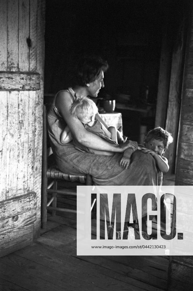 MIGRANT FAMILY, 1936. A migrant mother sitting in the doorway with her children in Hale County, Alabama. Photograph by Walker Evans in 1936.